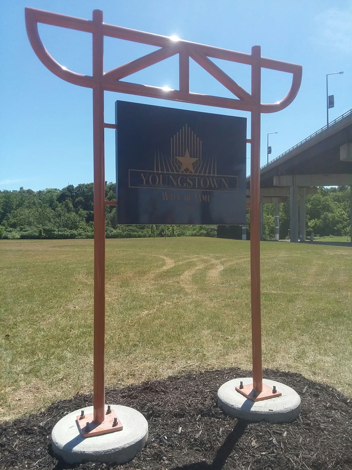 Copper truss-frame Youngstown Walk of Fame welcome sign with bridge in the background
