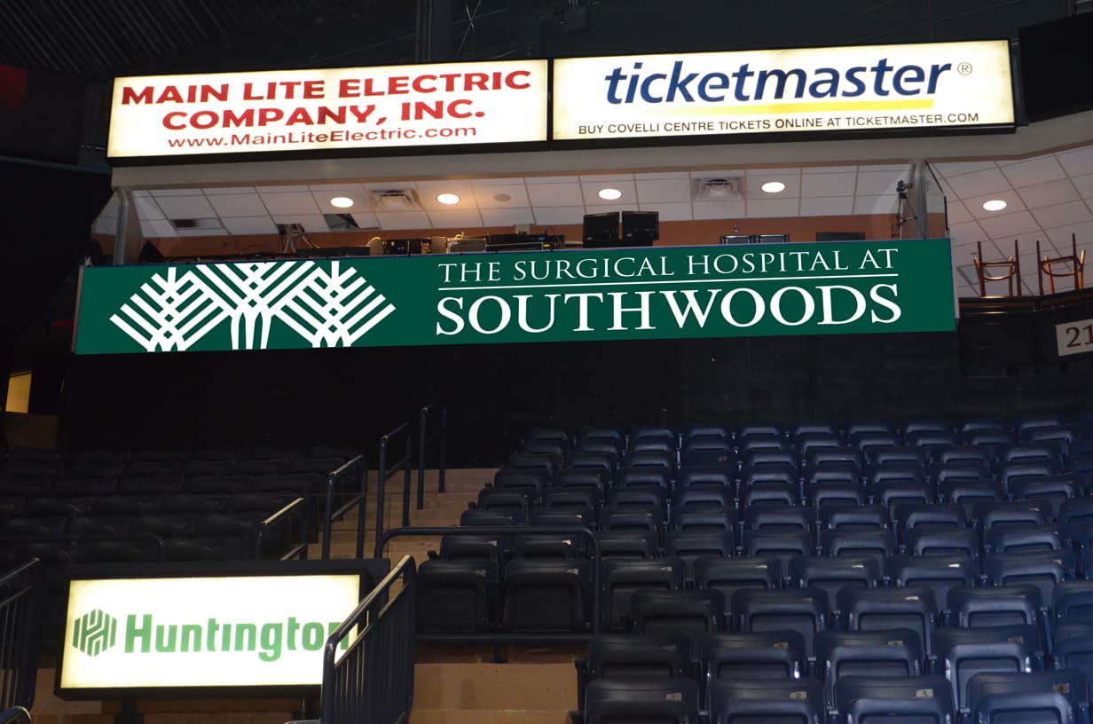Multiple sponsor signs above the Covelli Centre arena seating: Surgical Hospital at Southwoods, Ticketmaster, Main Lite Electric, Huntington
